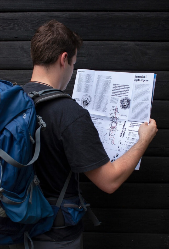 A person outdoors reading the Hrvatski Planinar publication