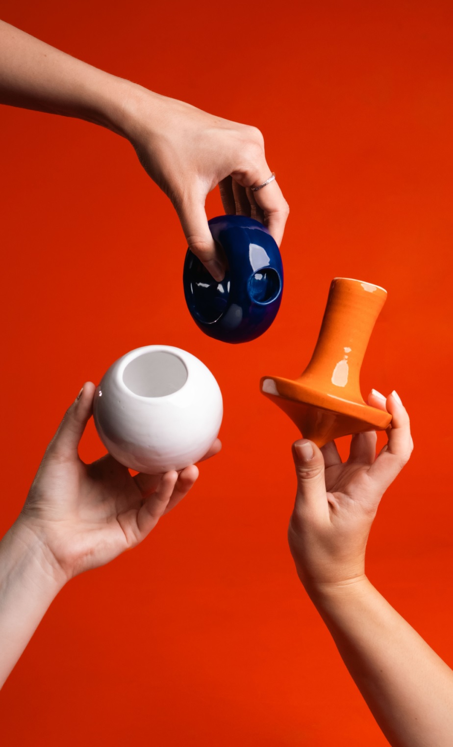 Hands holding colorful ceramic objects against a red background