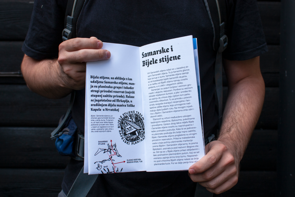 Hiker holding the publication open to an illustrated article