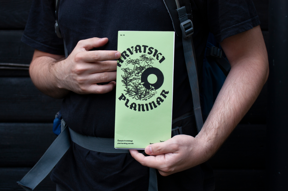 Hiker holding the folded green Hrvatski Planinar cover