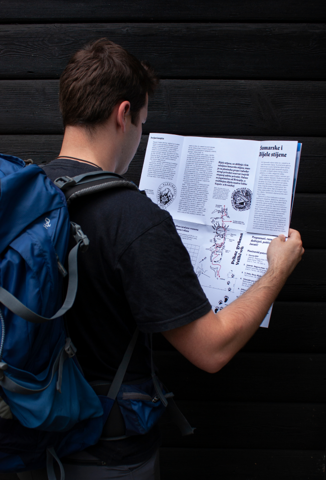 Hiker with a backpack reading the unfolded publication