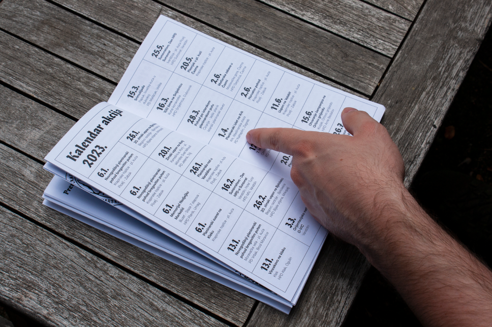 Hiker reading a calendar spread from the publication on a wooden table