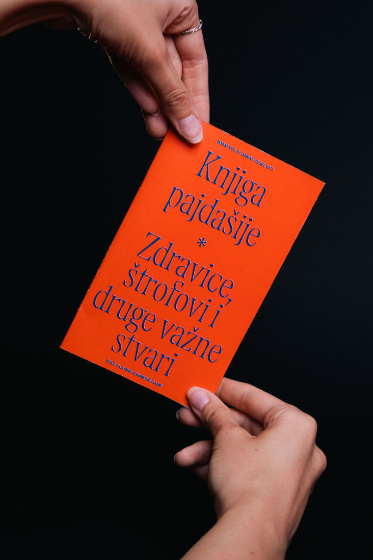 Hands holding the orange project book against a black background