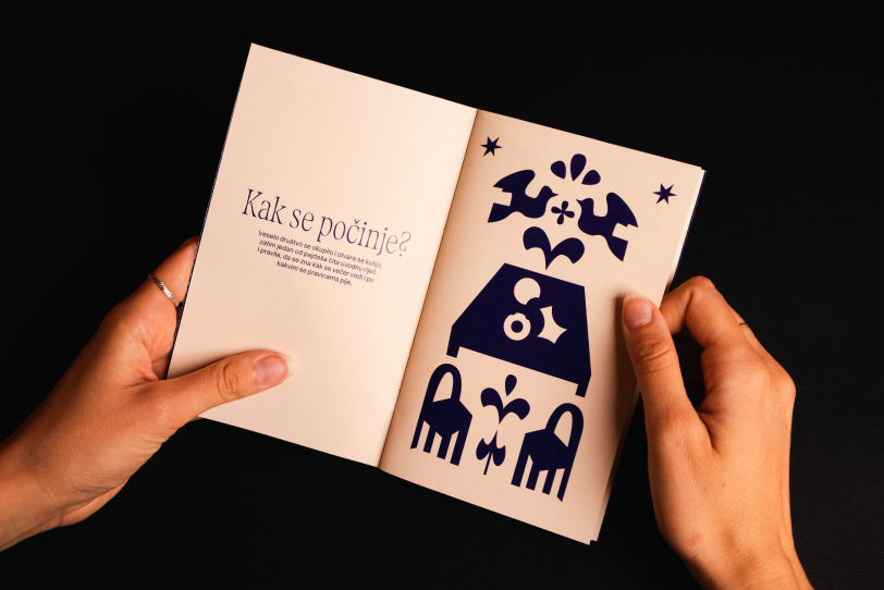 Hands holding an illustrated game booklet against a black background