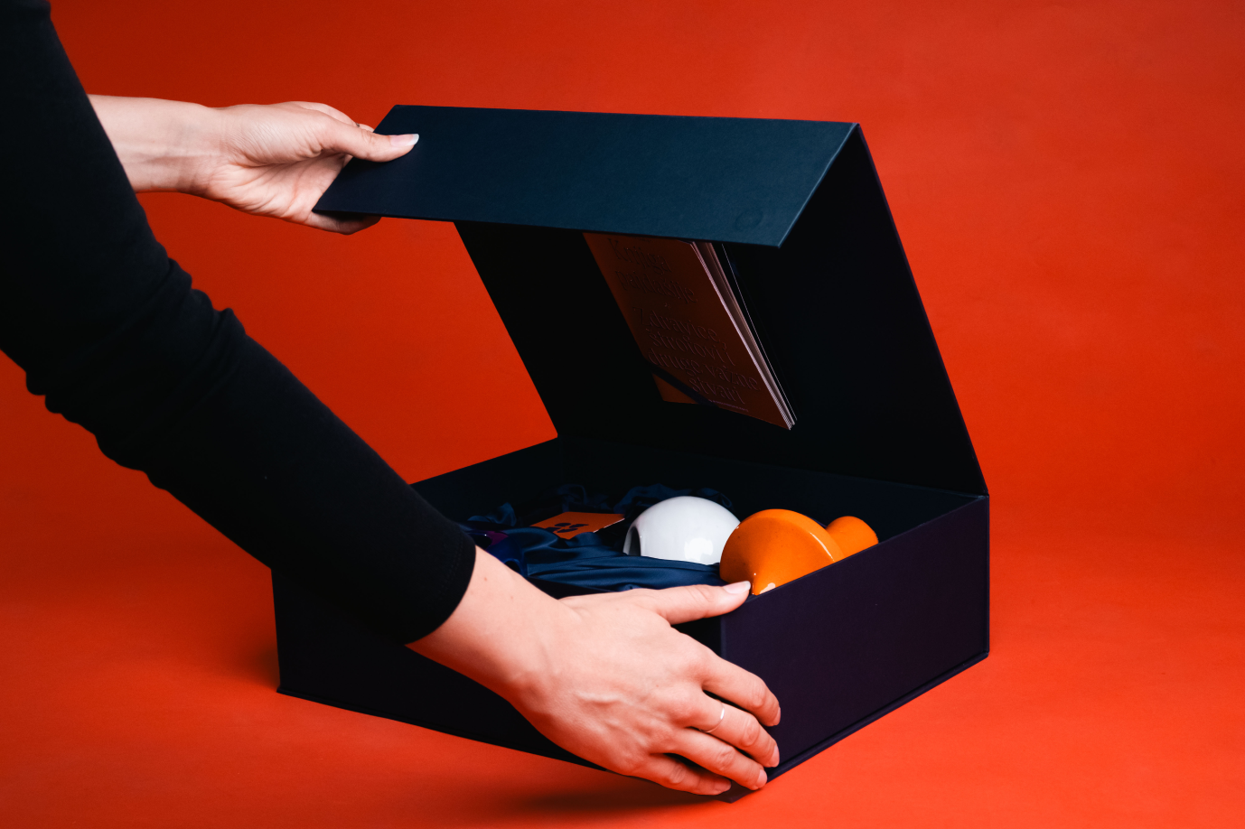 Hands opening a dark blue game box containing ceramic pieces