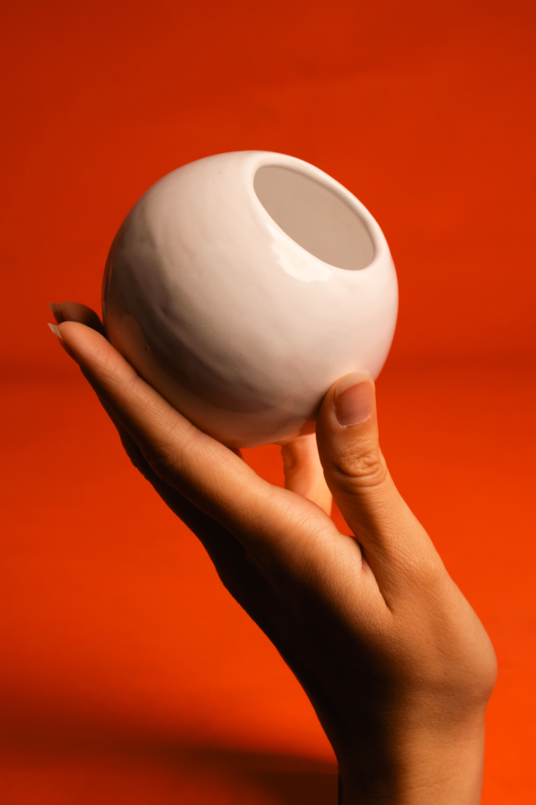 White ceramic game object held against an orange background