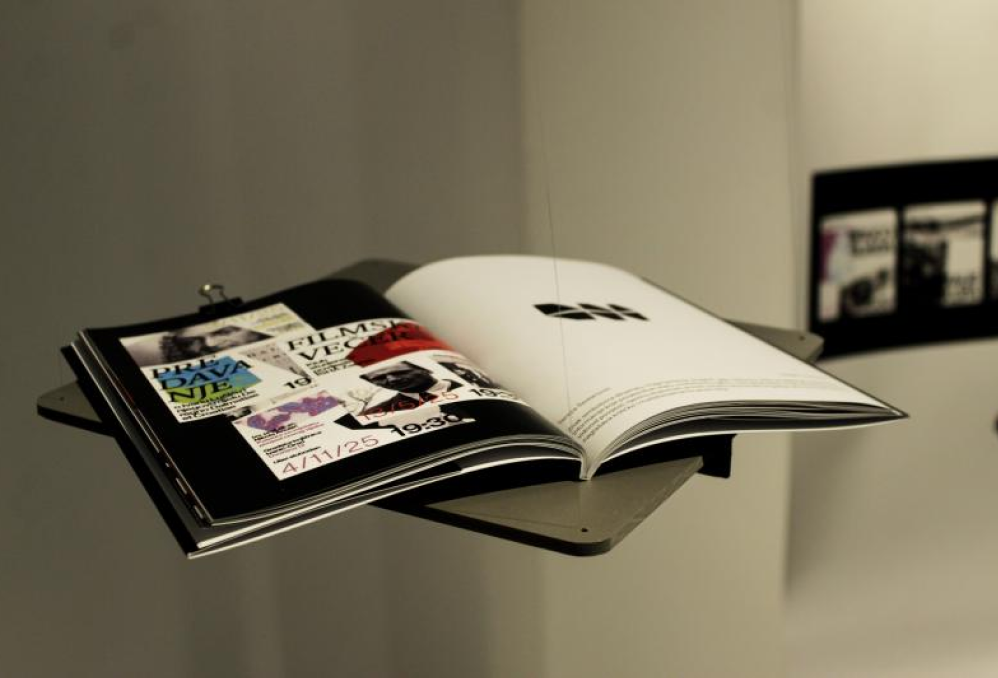 Open exhibition publication displayed on a gallery stand