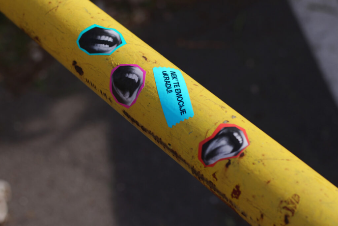KRADU14 promotional stickers attached to a yellow street pole