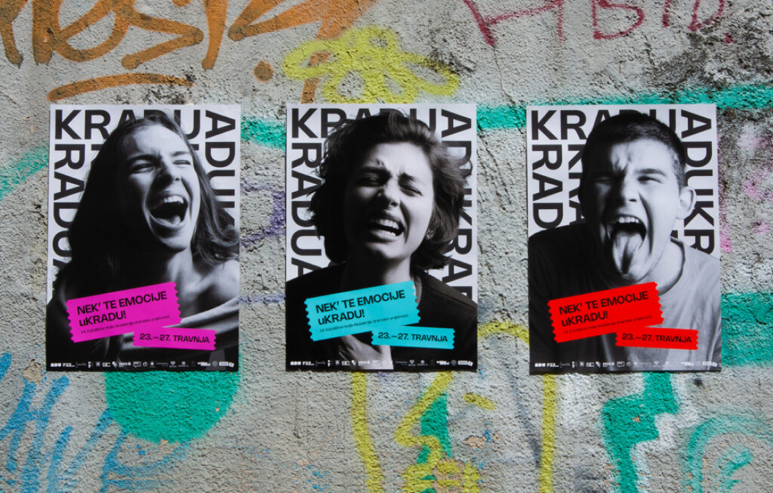 Three colorful KRADU14 posters displayed on a graffiti-covered wall