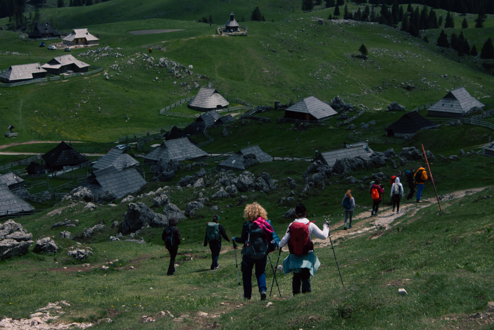 A group of hikers descending toward a mountain village