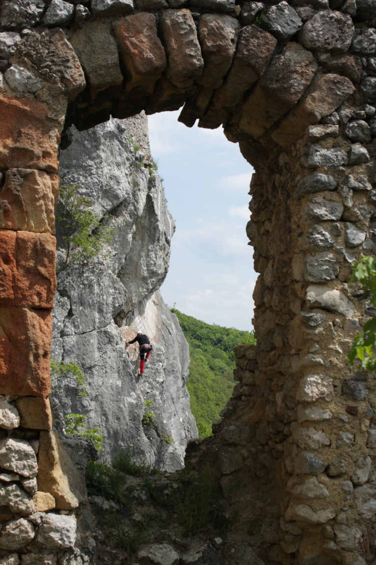 Climber visible through an old stone arch in the mountains