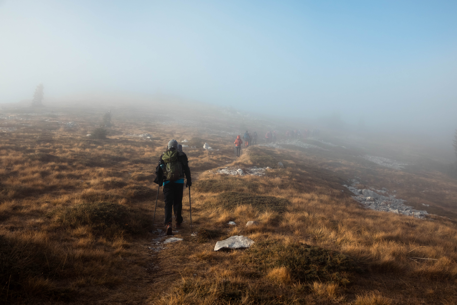 Hikers walking across a foggy mountain plateau
