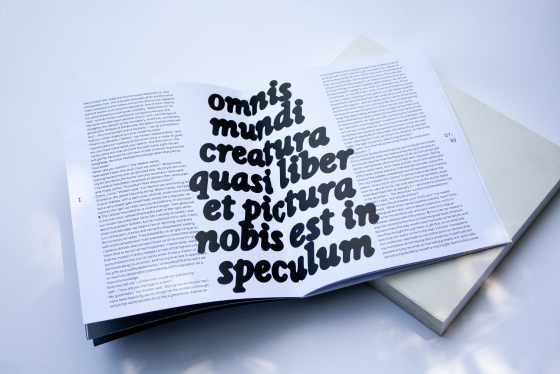 Open experimental book displaying large black typography
