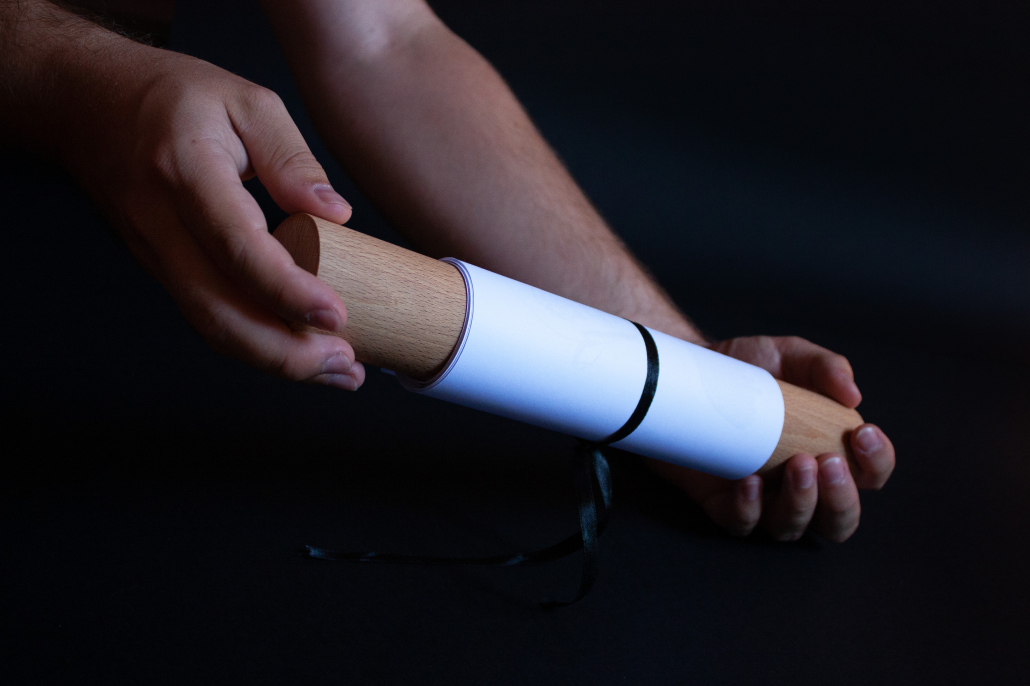 Hands holding a rolled illustrated scroll against a dark background