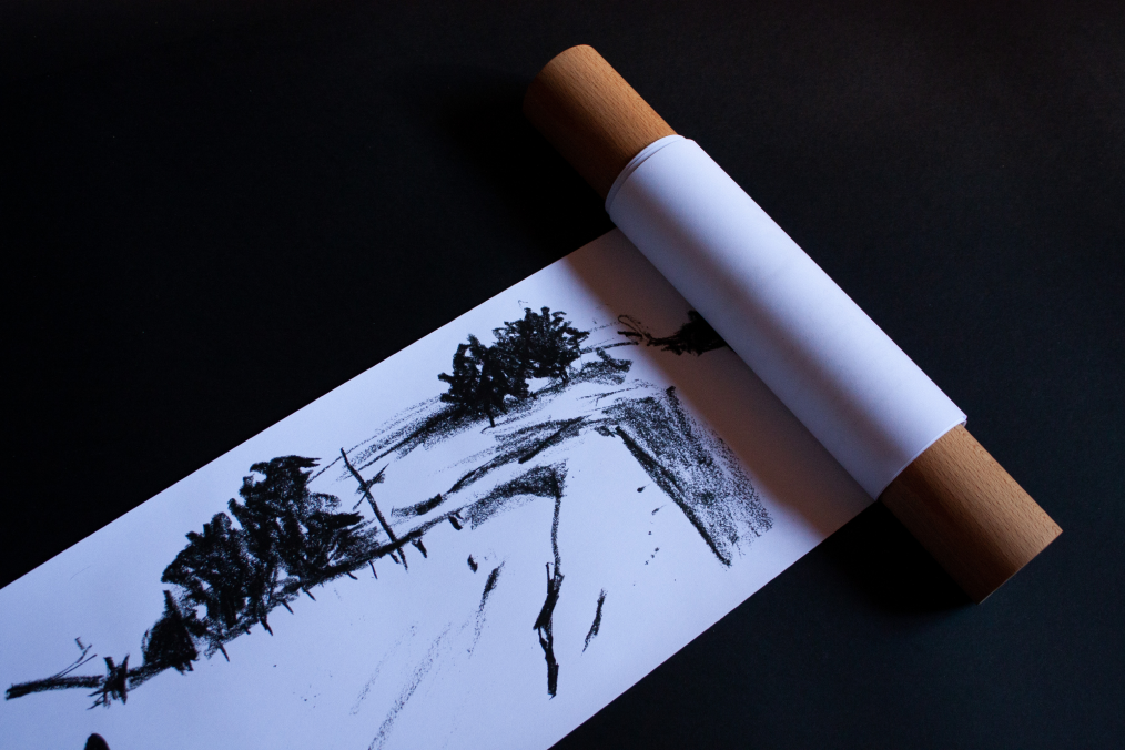 Illustrated landscape scroll partially unrolled between wooden rollers