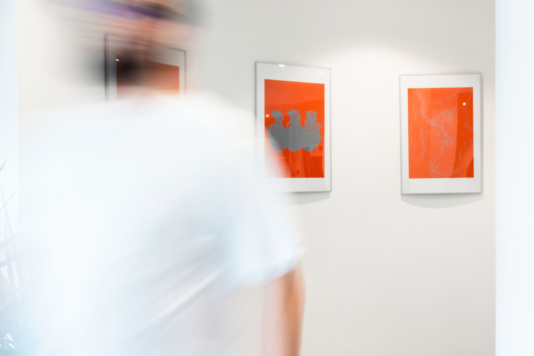 Visitor walking past orange artworks at the Varijacije exhibition