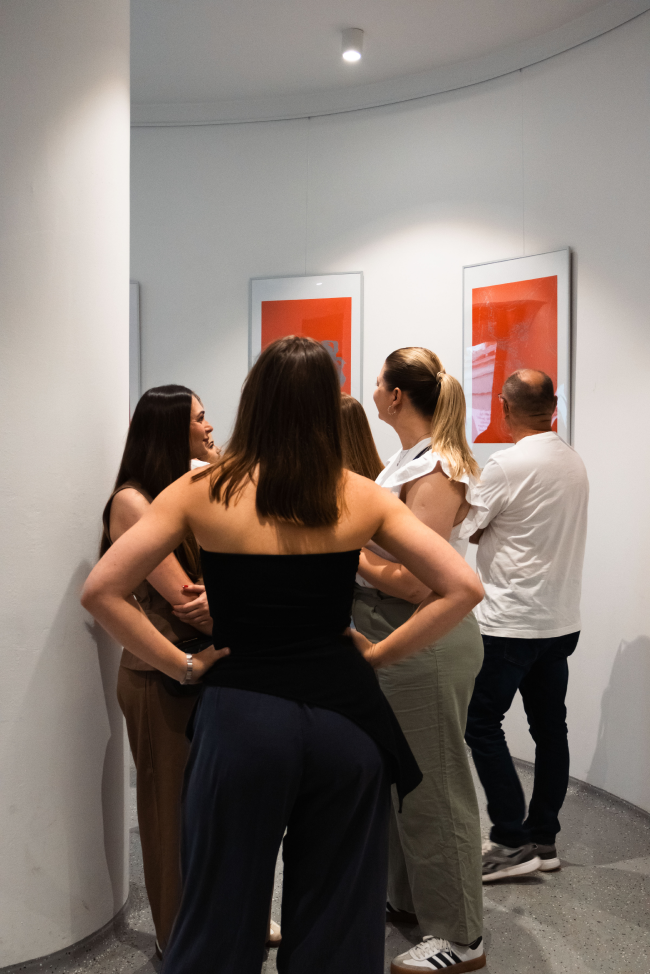 A group of visitors gathered around the exhibition artworks