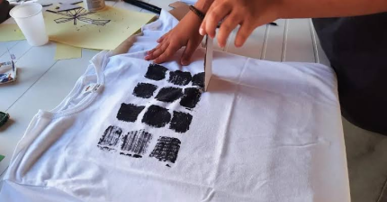 Participant printing a repeated pattern onto a white fabric bag
