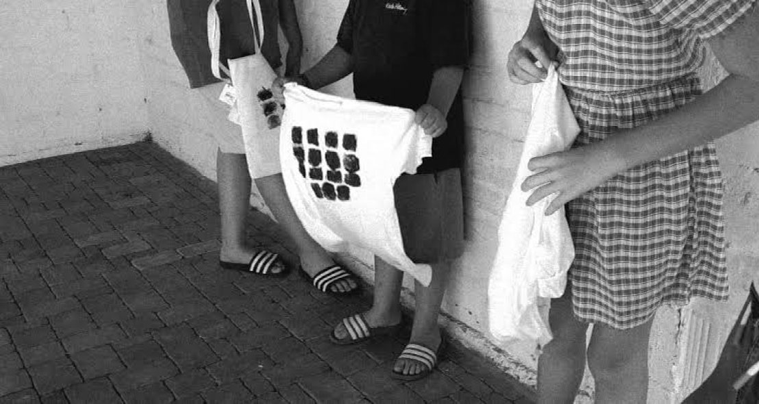 Black and white photograph of participants holding printed tote bags